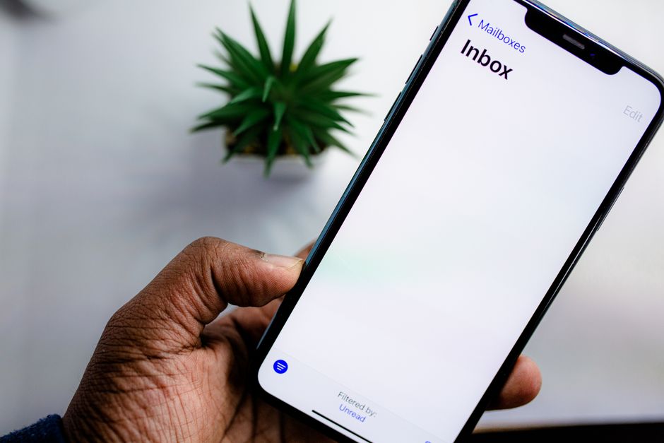 A split-screen image of a person holding a phone with an SMS conversation and a laptop with an email inbox open.